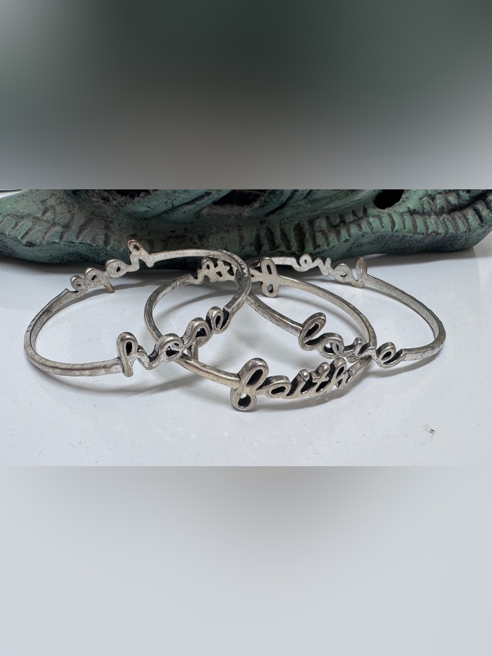 Premier Design Silver bangles feature cursive lettering faith", "hope"and
"love"